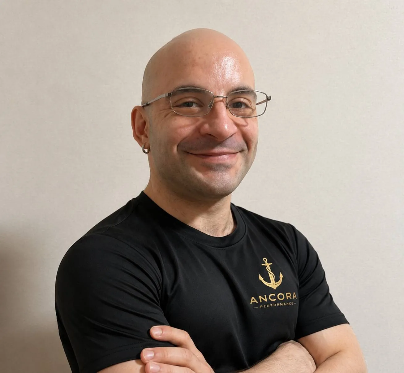 Portrait of Samuel Ancora, personal trainer in Osaka, smiling with arms crossed and wearing glasses and a black ANCORA PERFORMANCE T-shirt.